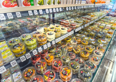 Kühltheke im Supermarkt mit vielen verpackten Dips, Salaten und Antipasti in Kunststoffschalen.